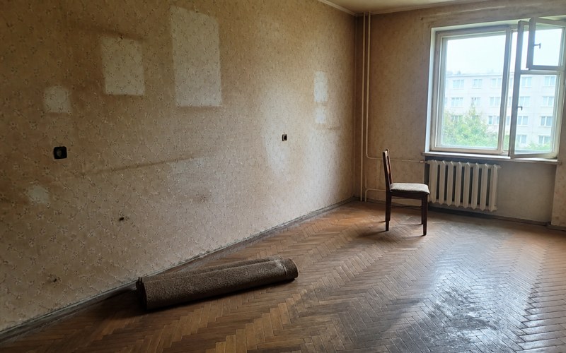 Iztukšota dzīvokļa istaba ar gaišiem laukumiem uz tapetēm, kur stāvējušas mēbeles