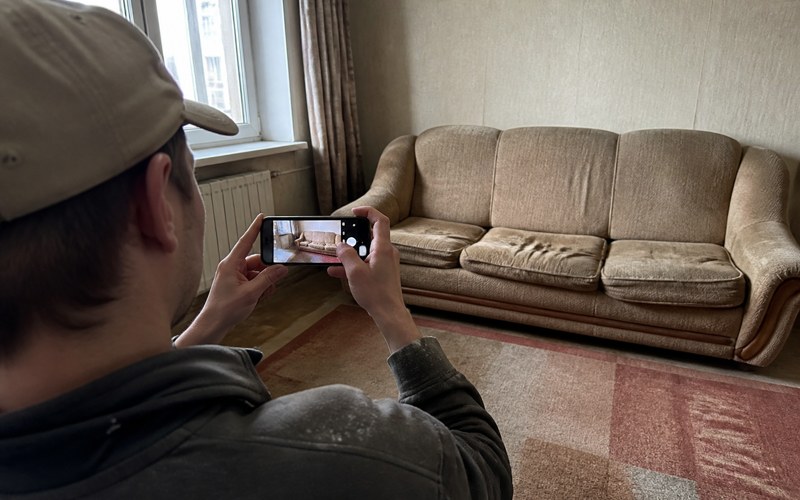 Klients fotografē vecu dīvānu ar telefonu, lai saņemtu cenu