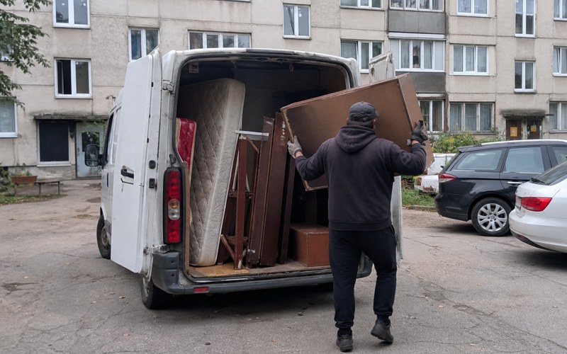 Nemarķēta furgona kravas nodalījums, piekrauts ar vecām mēbelēm un matraci
